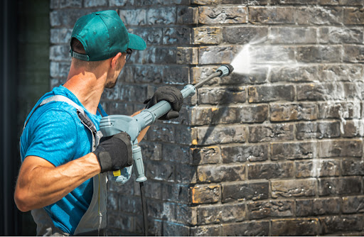 a worker powerr washing a building's exterior