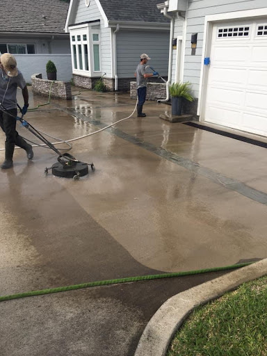 Poseidon Power Washers clean the driveway of a home.