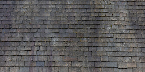 A gray slate roof is pictured with black marks.