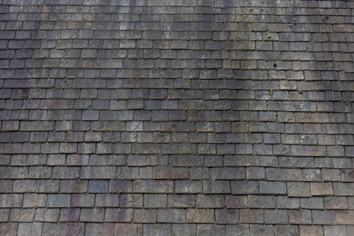 A gray slate roof is pictured with black marks.